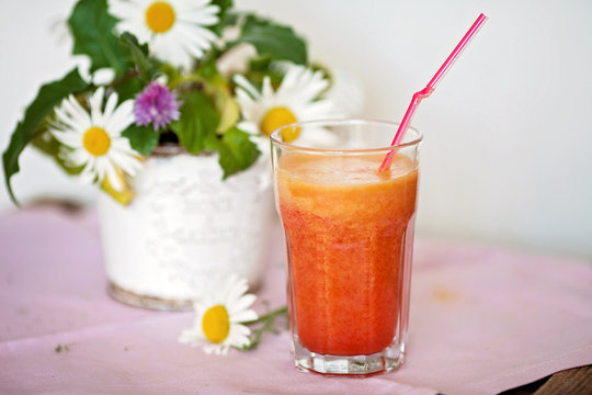 Strawberry, orange and apple fresh in a glass with a lined straw