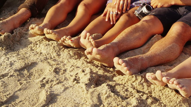 Group of young people with feet in sand