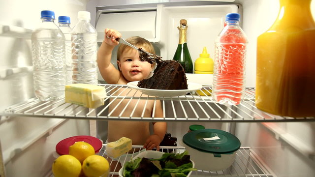 Baby eating chocolate cake in refrigerator