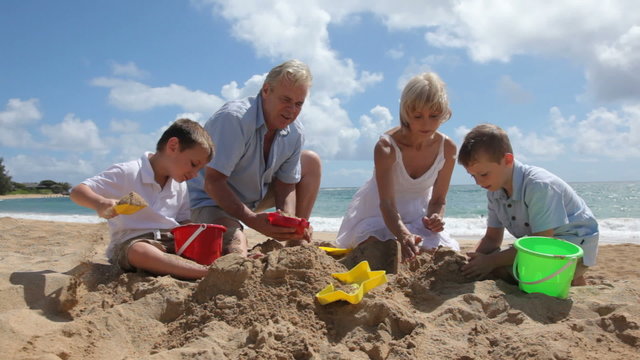 Grandparents play with grandchildren at beach