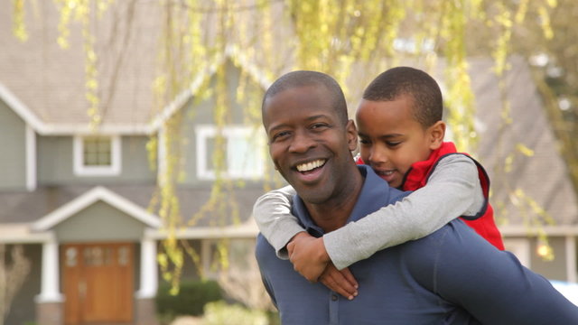 Portrait of African American father and son outdoors in yard