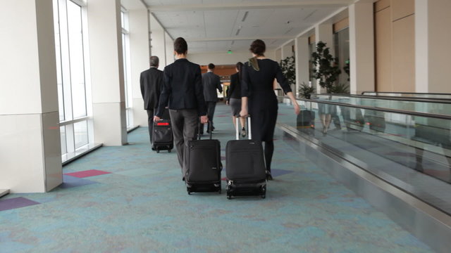Business people walk through airport with luggage
