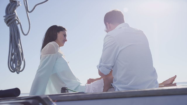 Young couple sit on sailboat together. 