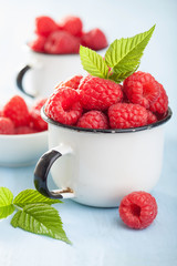 fresh raspberry in enamel cup over blue background