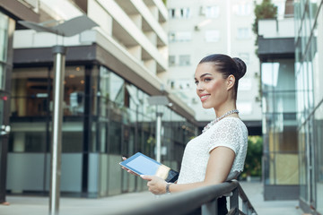 Young businesswoman holding a digital tablet in hands outdoors