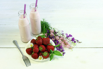 Fresh strawberries, a bowl with chamomile on a wooden background