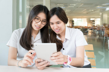 Two Asian student with uniform in classroom with electronic tabl