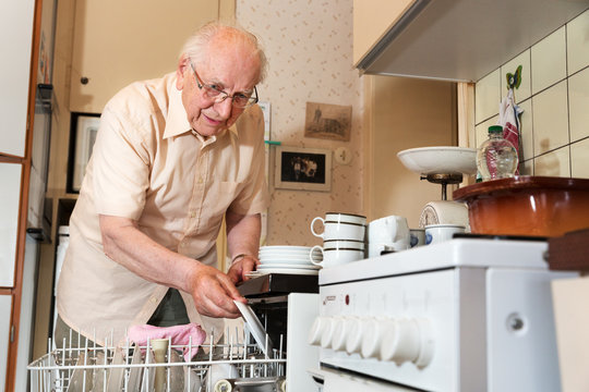 Elderly man unloading the dishwasher