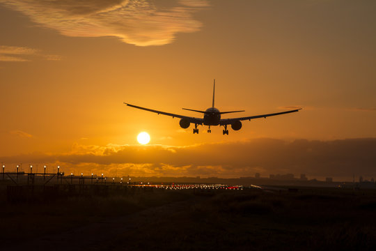 Airplane Is Landing During A Beautiful Cloudy Sunrise.