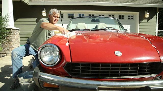 Grandfather and young boy washing car together