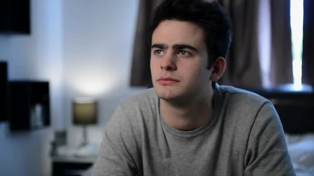 Close up portrait of depressed teenage boy in his bedroom