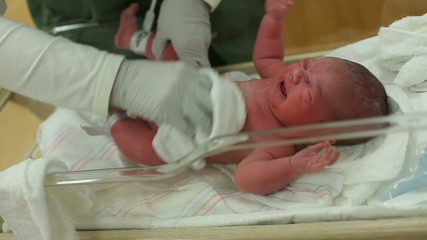 Newborn baby in hospital is cleaned by nurse