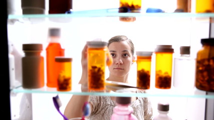 Woman looking for pills in medicine cabinet