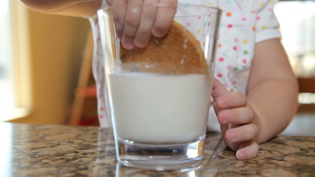 Child dipping cookie in milk