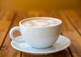 Cup of coffee with heart pattern in a white cup on wood table