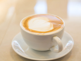 Cup of coffee with heart pattern in a white cup on