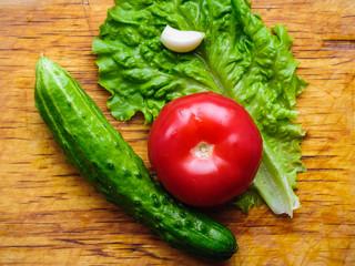 Raw fresh cucumbers, tomatoes and salad on farmer yellow wooden