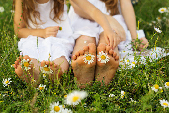 Two pair of childs feets with daisy flowers 