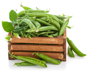 Green peas in wooden box. Isolated on white background