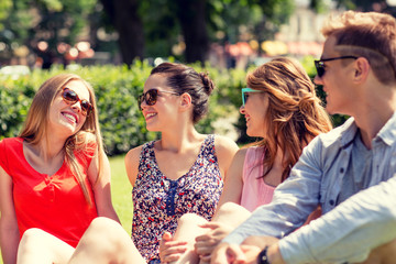 group of smiling friends outdoors sitting in park