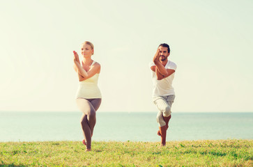 smiling couple making yoga exercises outdoors