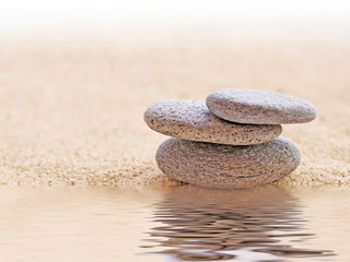 Fototapeta na wymiar Zen stone stack and sand, water reflections