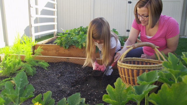 Mother and daughter planting seeds in garden