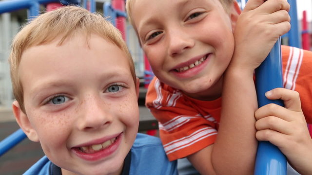 Two young boys at playground making silly faces