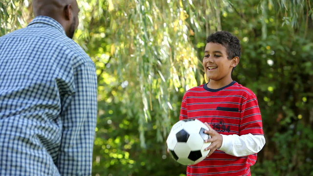 African American father and son playing with a football 