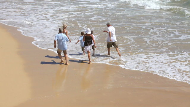 Multi-generation family running on beach together