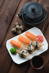 Sushi set on a white glass dish with soy sauce and tea, top view