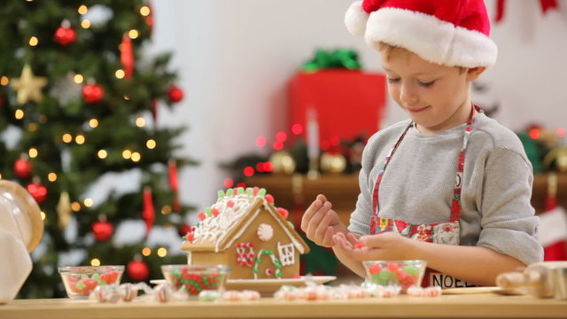 Young boy making Christmas gingerbread house