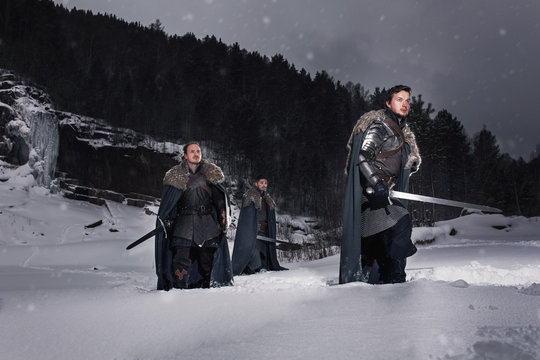 Medieval knights with swords in armor walking in snow