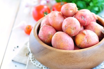 wooden plate with fresh Potatoes on white background