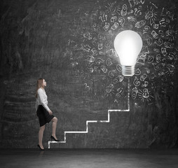 Young lady is going up via the drawn ladder to the huge lightbulb. A concept of ideas in business.