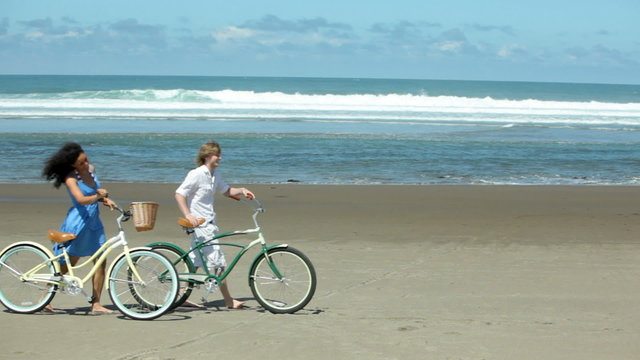 Couple walk with bicycles along coastline