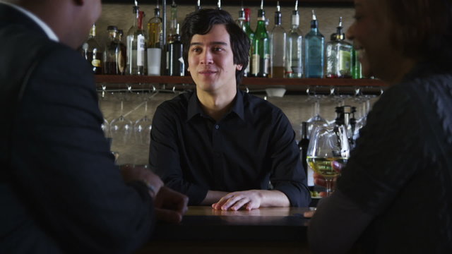 Bartender talks to customers and serves drinks
