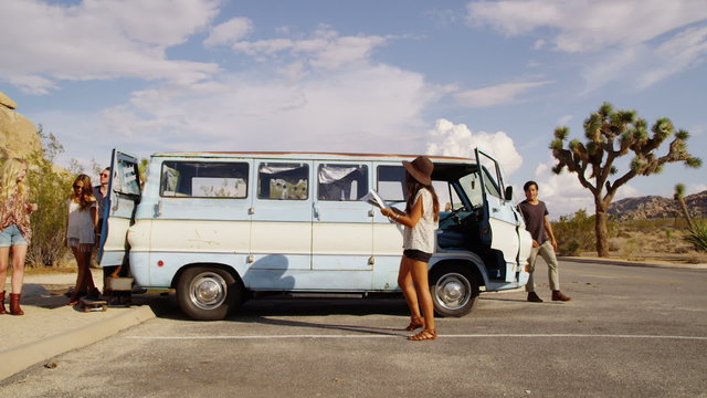 Group of young people on road trip look at map