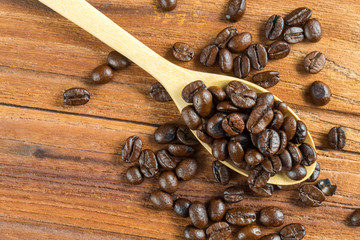 Coffee bean on wooden spoon, wooden table background