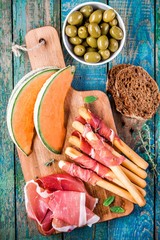 breadsticks with prosciutto, melon, olives and bread