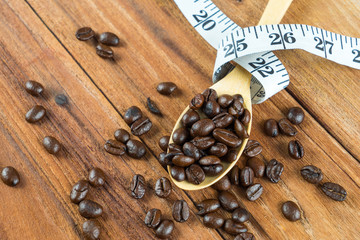 Obraz na płótnie Canvas Coffee bean on wooden spoon, tape measure on wooden background