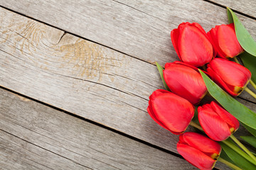 Naklejka na ściany i meble Fresh red tulips bouquet over wooden table background