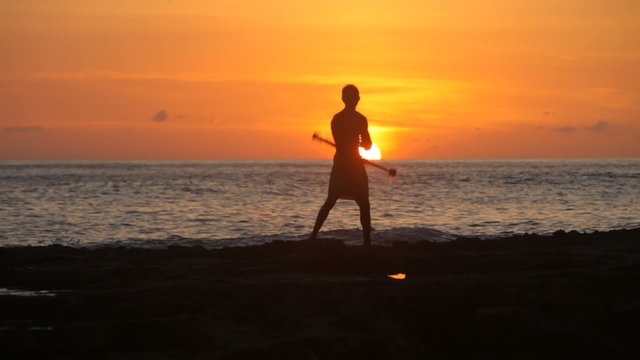 Hawaiian fire knife dancer performs at sunset