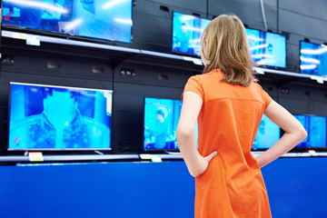 Teenager girl looks at LCD TVs in shop