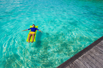 Young happy man relaxing on inflatable mattress in the sea