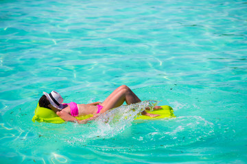 Woman relaxing on inflatable air mattress at turquoise water