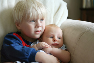 Toddler Brother Holding Baby Sister on Couch