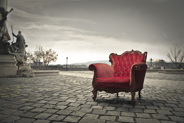 Red chair placed in a square - obrazy, fototapety, plakaty