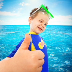 Little boy with thumbs up gesture at sea