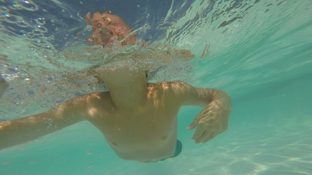 Young boy swimming in pool underwater, POV video